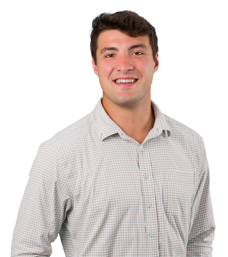 Alex Doga is in a white shirt with a light plaid pattern and smiling for a photo