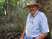 Dr. Charles Allen leaning against a tree